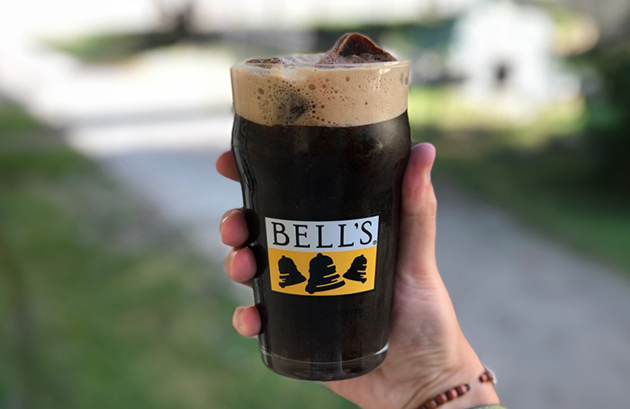 A hand holds a large Bell's pint glass filled with Porter and ice cubes made out of one of our stouts.