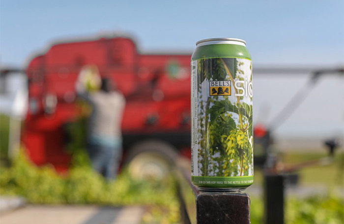 A can of Sideyard sits in focus in front of a hop harvester.