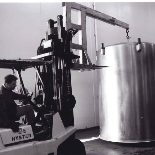 a black and white photo of a forklift carrying a large vat from beer history