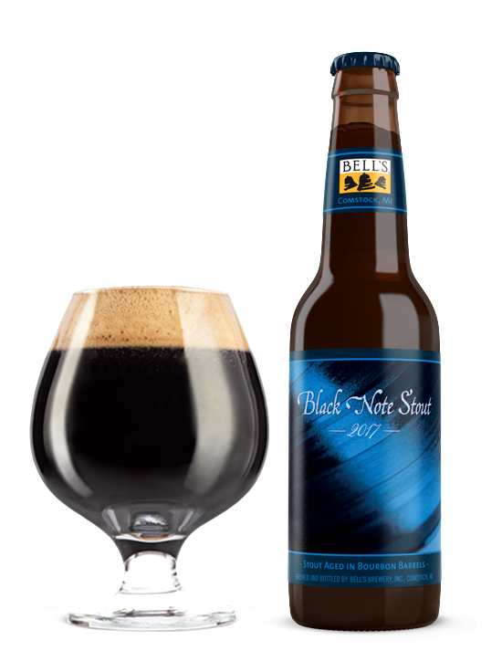 A full snifter glass sitting next to a bottle of Black Note Stout