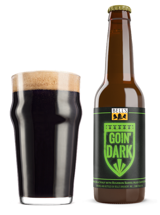 A full nonic glass next to a bottle of Goin' Dark