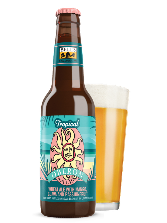 A bottle of a Tropical Oberon Ale sitting in front of a front glass