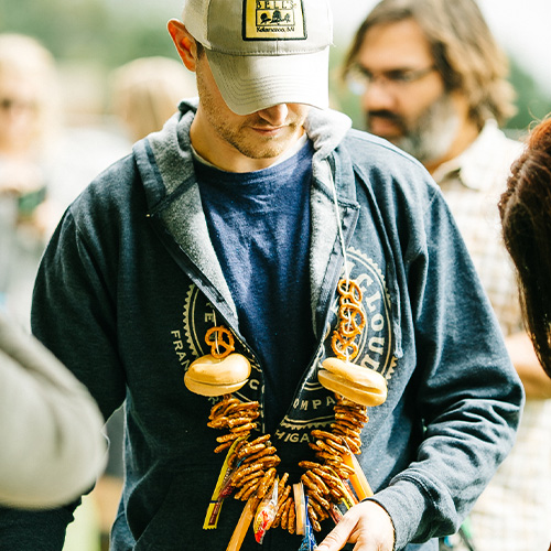 someone wearing a necklace of food from the bells funvitational 30th anniversary beer festival