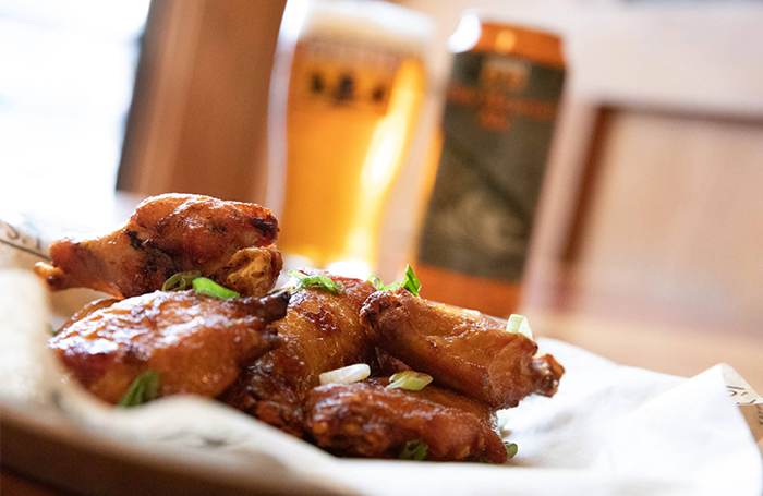 A plate of chicken wings, with a can and pint of Two Hearted in the background