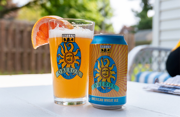 A can of Oberon next to a pint glass with an orange liquid in it with a grapefruit wedge on top