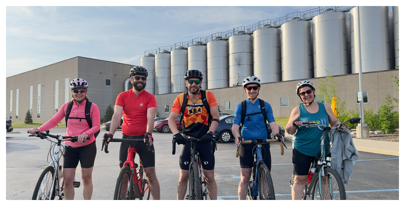 A group of five people on bicycles in front of the brewery