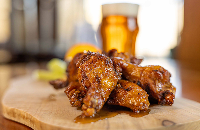 A plate of chicken wings with a beer in the background
