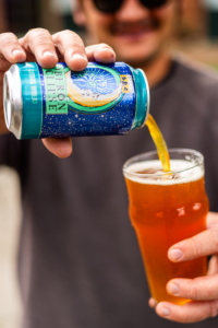 A man pouring a can of Oberon Eclipse into a pint glass